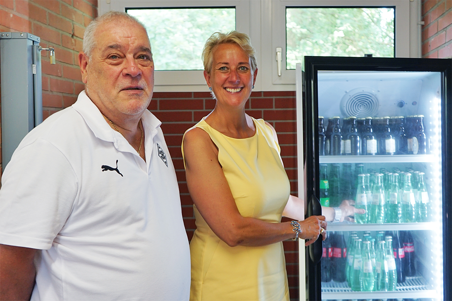Bei der offiziellen Übergabe bediente sich Stephanie Krähenhöfer, Leiterin der Waldnieler Geschäftsstelle der Volksbank Viersen, auf Einladung am neuen Flaschenkühlschrank.