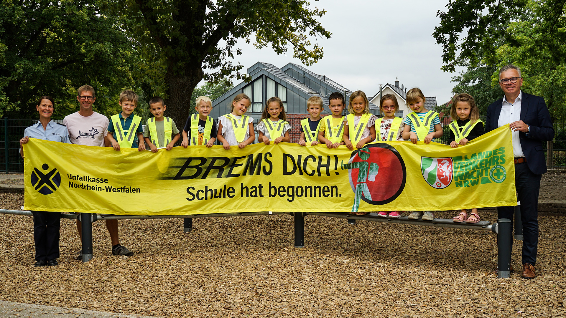Daniela Michiels, Bodo Dora, Christoph Pach (von links) und die Kinder der Schule am Lütterbach freuen sich über die reflektierenden Sicherheitskragen, die von der Volksbank Viersen gesponsert wurden.