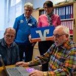 Werner Schroeren (Deutsche Rheuma Liga e. V., ganz rechts) arbeitet ehrenamtlich jeden Donnertag an dem neuen Laptop.