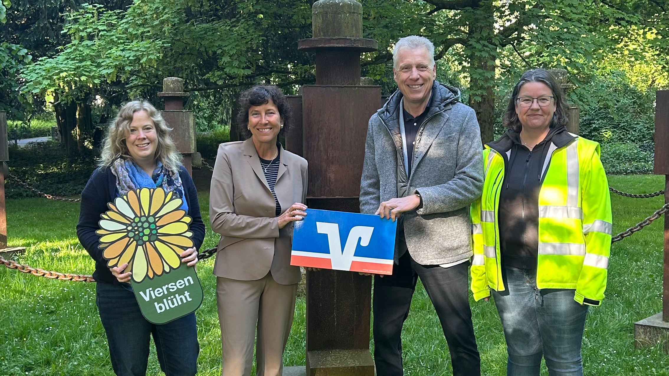 Mareike Backhausen (Koordination Citymanagement), Sabine Anemüller (Bürgermeisterin der Stadt Viersen), Jürgen Cleven (Vorstand der Volksbank Viersen) und Nicole Strucken (Sachbearbeitung Grünflächenunterhaltung) im Viersener Casinogarten vor den Skulpturen "Wächter der Kinder".