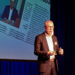 Jürgen Cleven steht auf der Bühne und spricht zum Publikum.