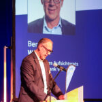 Bernd Wolfs steht am Mikrofon und spricht.