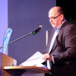 Carsten Waldhelm steht am Mikrofon und spricht zur Überreichung der silbernen Ehrennadel.